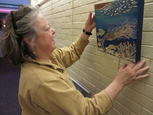 Bonnie and one of her mermaid pieces hanging in the gallery at Homeland Center Bonnie Bissett